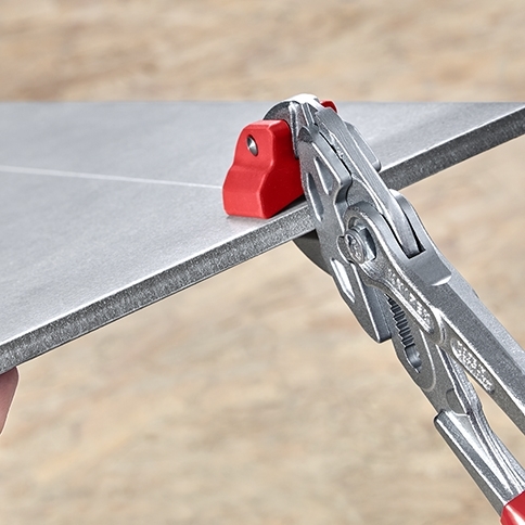 Obcęgi Knipex 91 13 250 ustawione na naciętej płytce ceramicznej