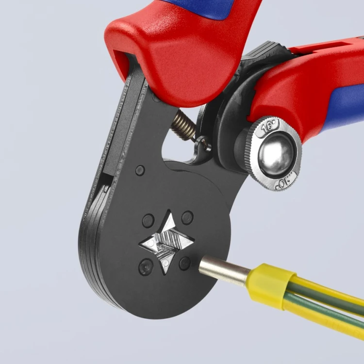 Szczypce Knipex 97 53 04 z samonastawną matrycą obok tulejki na żółto-zielonym przewodzie elektrycznym